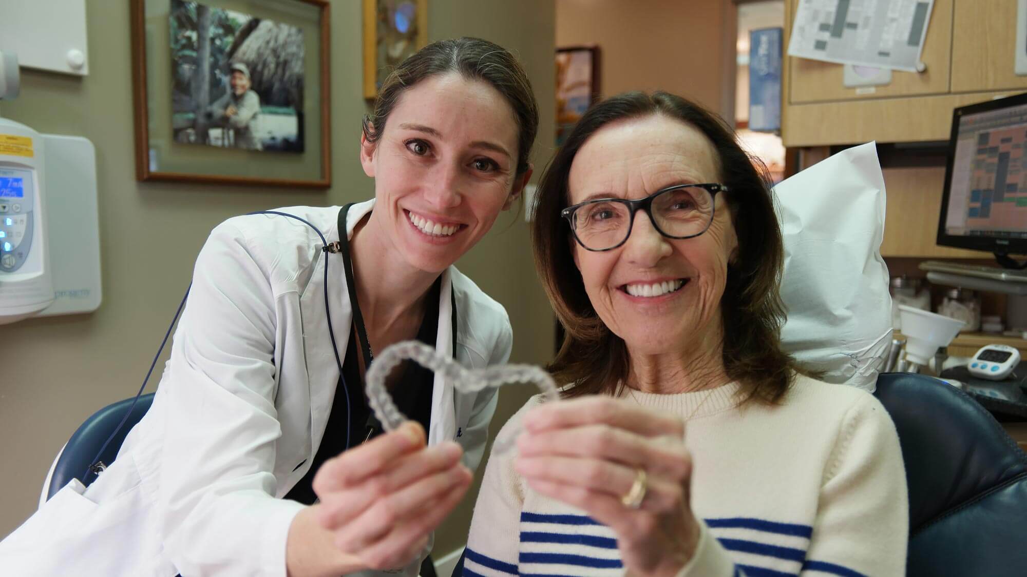 Doctor and patient holding up clear aligners.